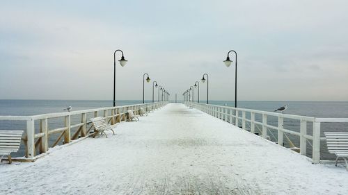 Pier on beach against sky