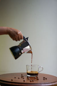 Close-up of hand pouring coffee in cup