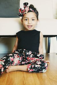 Portrait of smiling girl sitting on table at home