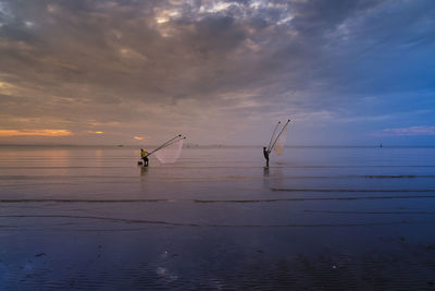 Silhouette man standing by sea against sky during sunset