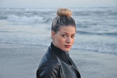 Side view portrait of confident woman with hair bun standing at beach