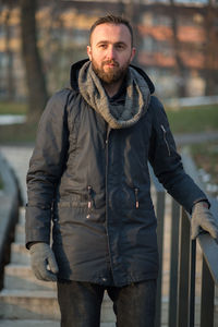 Portrait of young man in warm clothing moving down on steps at park