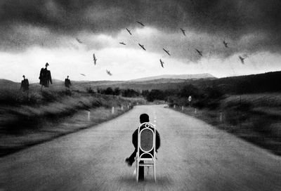 Rear view of person standing on street against sky