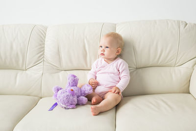 Cute baby girl sitting on sofa at home