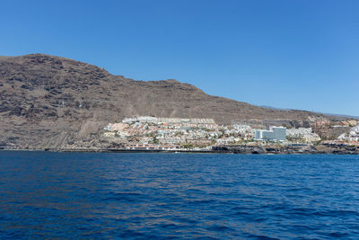 Sea by buildings against clear blue sky