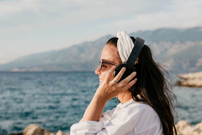 Portrait of woman using mobile phone against sea