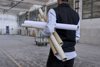 Male architect with cardboards standing in constructing building