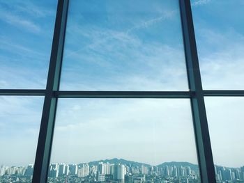 Close-up of cityscape against sky seen through window