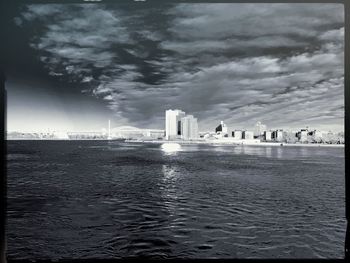 Bridge over sea against cloudy sky