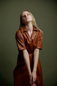 Portrait of young woman standing against yellow wall