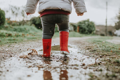 Low section of baby girl walking on puddle during rainy season