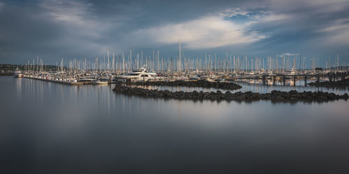 Sailboats in marina at harbor against sky