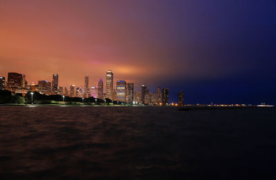 Illuminated buildings in city against sky at night