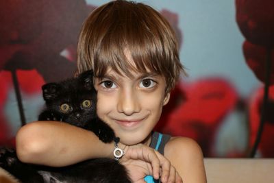 Portrait of boy embracing cat at home