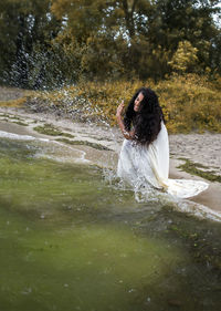 Full length of woman splashing water in lake