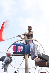 Low angle view of woman holding rope against sky