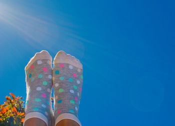 Low section of woman against blue sky