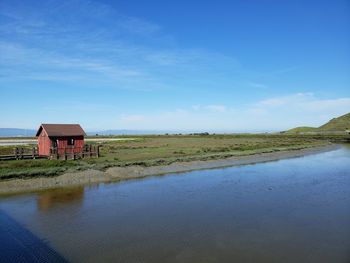 House by lake against blue sky