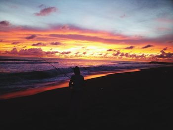 Silhouette people on beach against sky during sunset