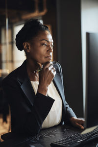Thoughtful businesswoman with hand on chin working at office