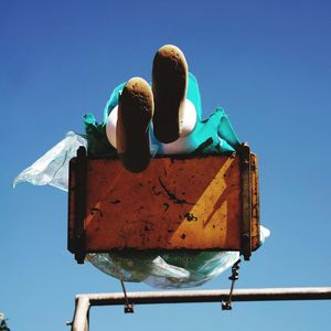 Low angle view of woman swinging against clear blue sky