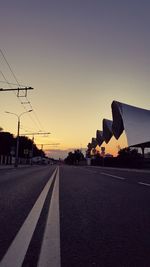 Road by city against sky during sunset