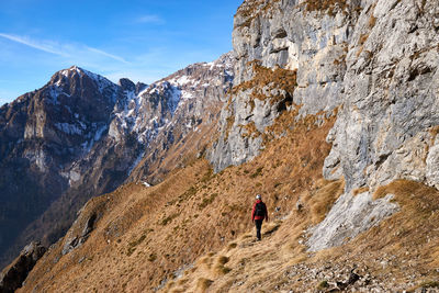 Rear view of man on rocky mountain against sky