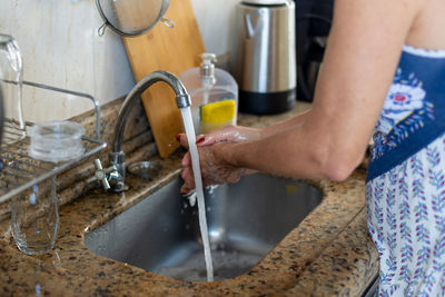 A woman, in the kitchen, washing her hands thoroughly before cooking. healthy eating