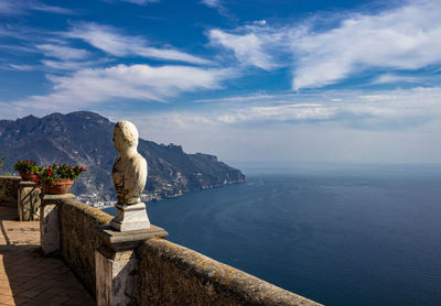 Statue by sea against sky