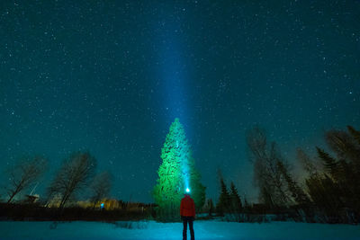 Rear view of woman on snow field against sky at night