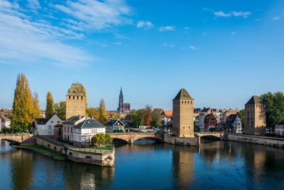 Bridge over river by buildings against sky in city