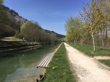 Scenic view of canal by trees against sky