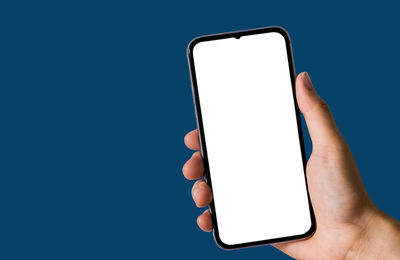 Low section of person holding smart phone over white background