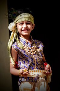 Portrait of smiling girl standing against black background