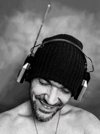 Smiling shirtless man wearing hat while listening music