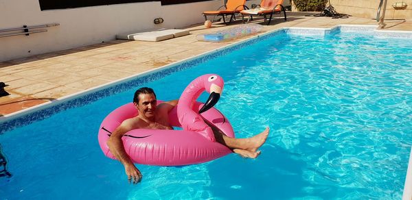 Full length portrait of man relaxing in inflatable ring at swimming pool