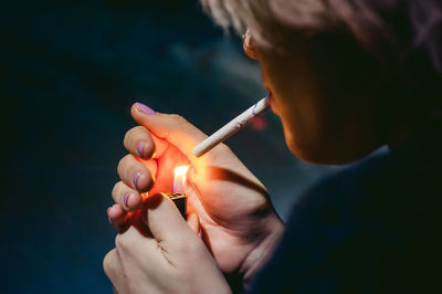 Close-up of young woman lighting cigarette