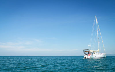 Sailboat sailing in sea against blue sky