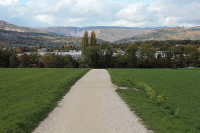 Road amidst field against sky