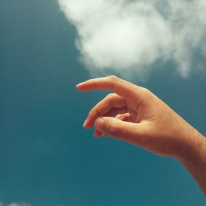 Close-up of person hand against sky