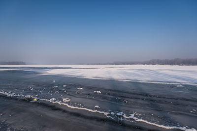 Scenic view of snow covered land against clear blue sky