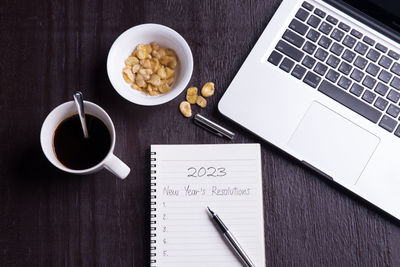 High angle view of coffee and book and laptop and objects on table