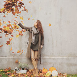 Full length of woman standing on wall during autumn