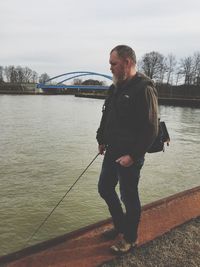 Man standing on bridge over river against sky