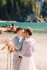 Couple embracing while standing at riverbank