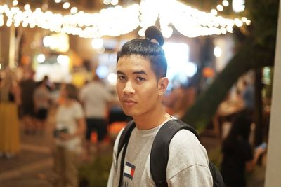 Portrait of boy standing against illuminated light at night