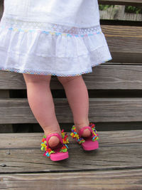Low section of girl with pink footwear climbing on plank