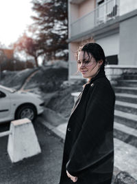 Young woman looking down while standing by car