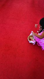 High angle view of girl with petals on red surface