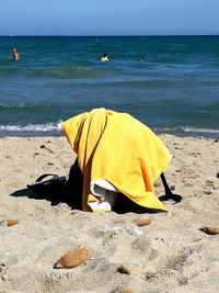 Woman lying on beach by sea against sky